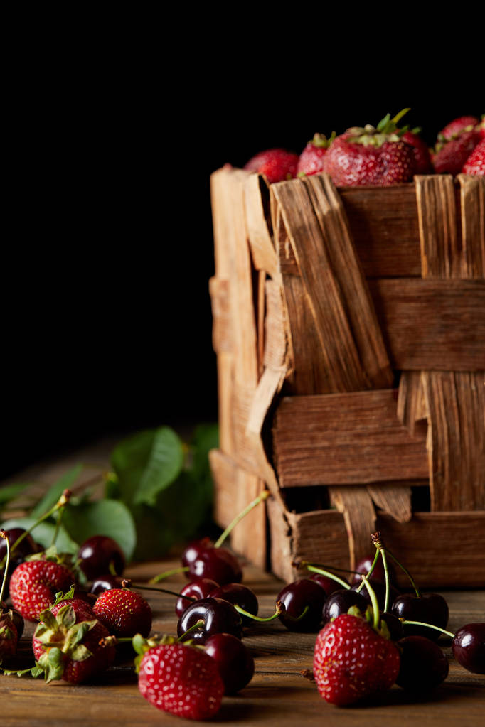 cerises mûres et fraises sur la surface en bois avec des feuilles et boîte rustique sur noir
 - Photo, image