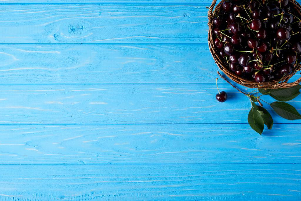 top view of red cherries in basket on blue wooden surface - Photo, Image