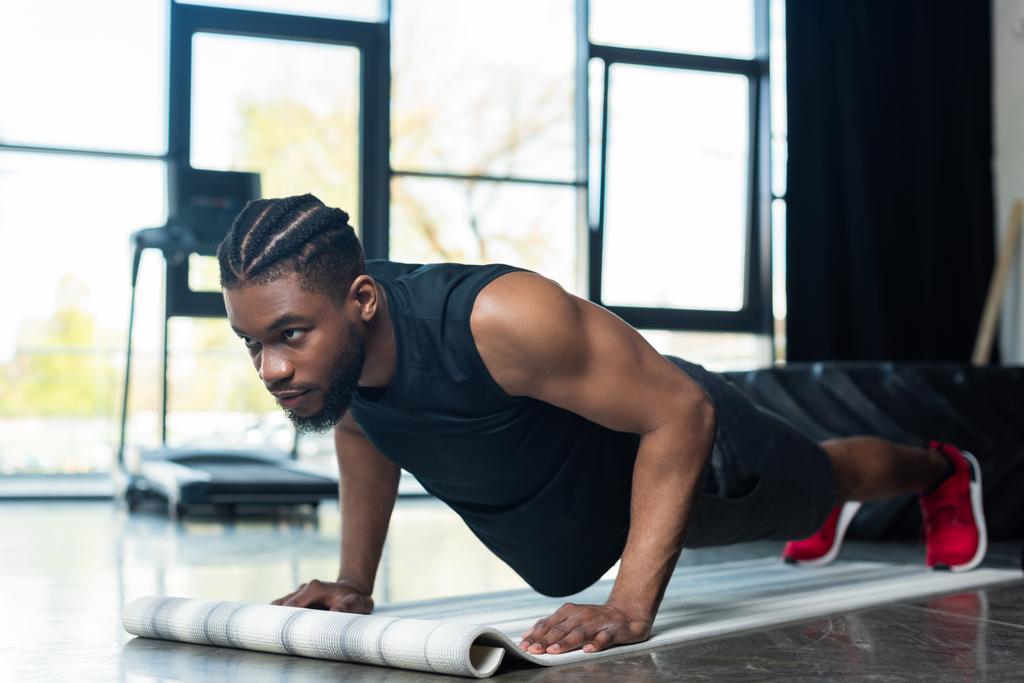 μυϊκή αφροαμερικάνος αθλητής κάνει push ups και αναζητούν μακριά στο γυμναστήριο - Φωτογραφία, εικόνα