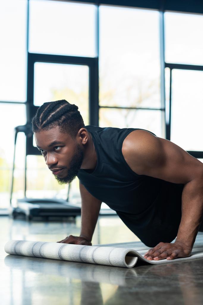 focused muscular african american man doing push ups in gym - Photo, Image
