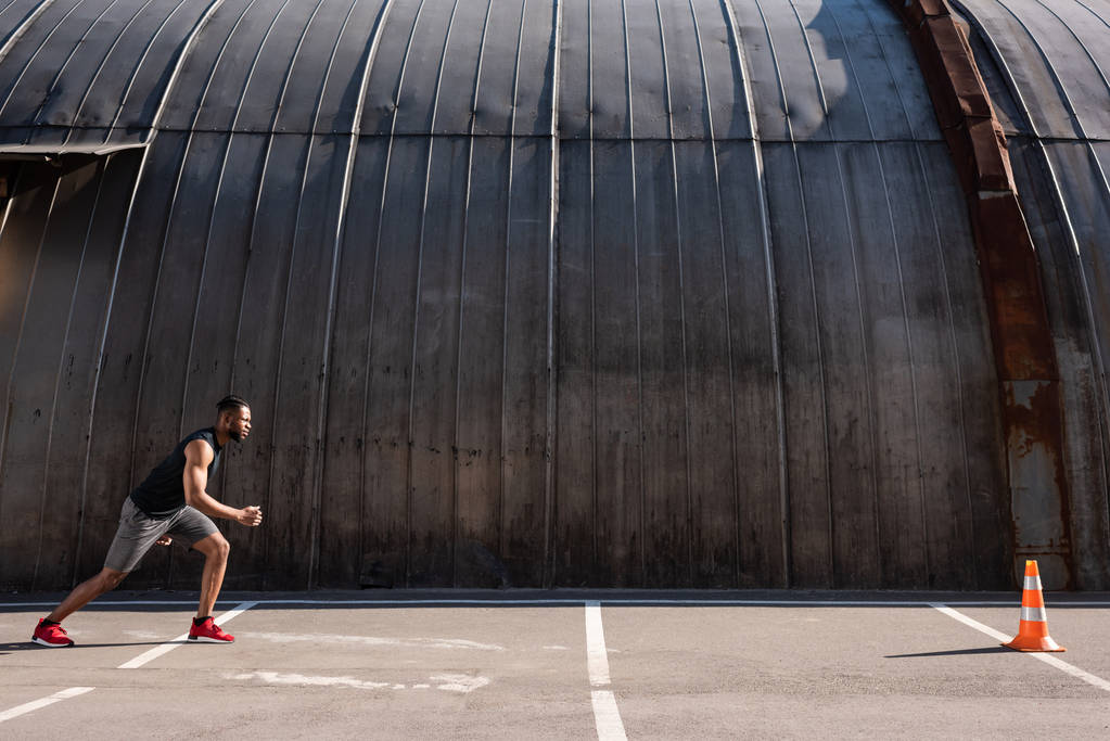 боковой вид молодого афроамериканца, бегущего по улице
 - Фото, изображение