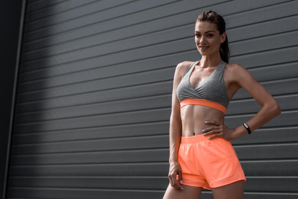 usmívající se sportovkyně pózuje v oblečení s fitness tracker - Fotografie, Obrázek
