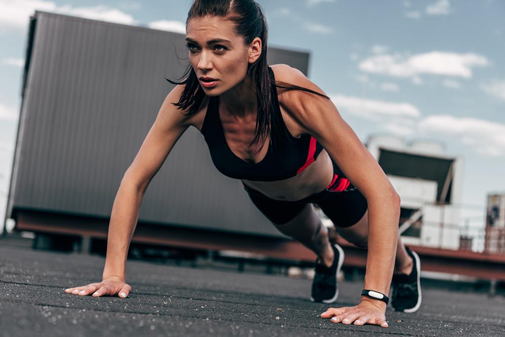 Koncentrovaná sportovkyně dělá push up na asfaltu v městě - Fotografie, Obrázek