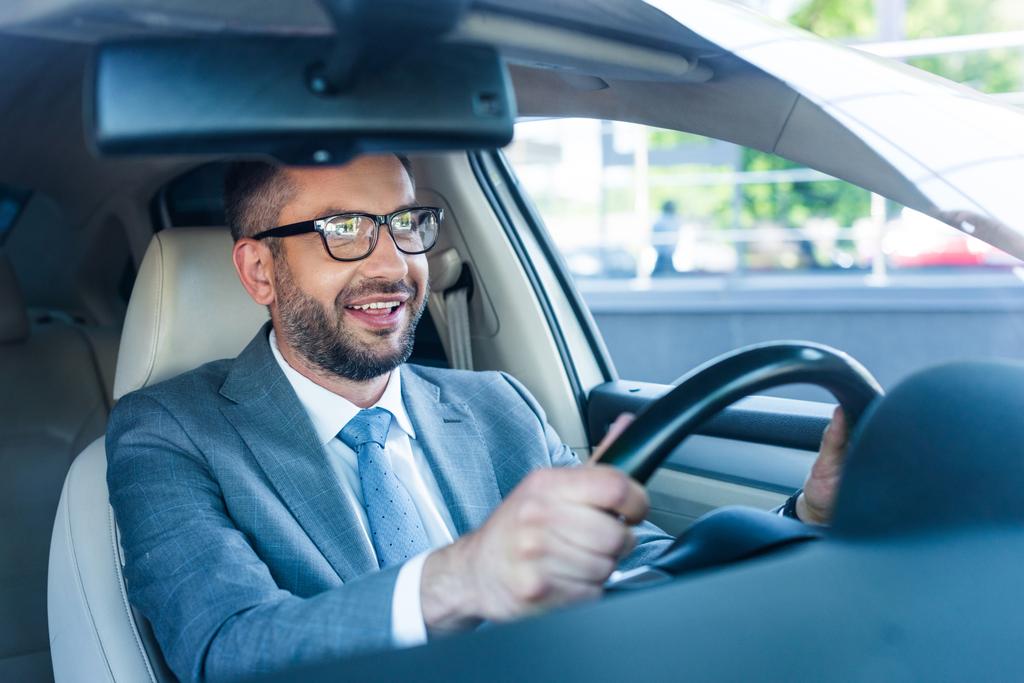 portrait d'un homme d'affaires souriant en costume et lunettes au volant d'une voiture seule
 - Photo, image