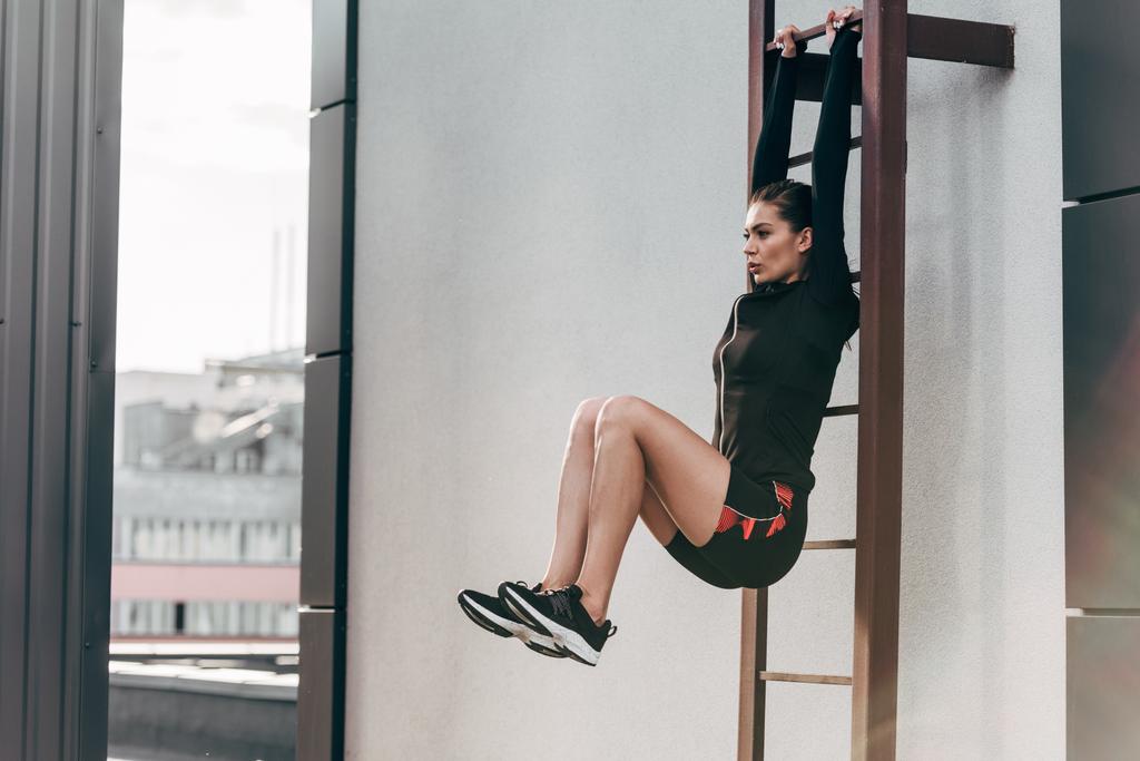 deportista atractiva haciendo abdominales en la escalera en el techo
  - Foto, Imagen