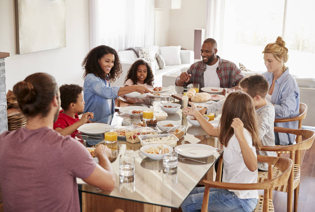 Dos familias disfrutando de la comida en casa juntas
 - Foto, Imagen