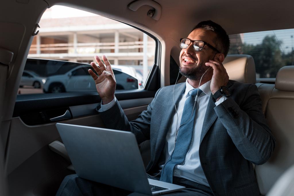 biznesmen w słuchawki z laptopa słuchania muzyki w samochodzie - Zdjęcie, obraz