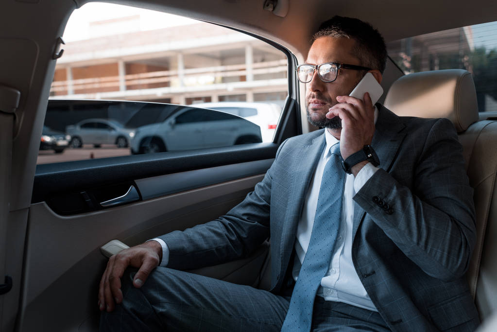 uomo d'affari che parla su smartphone sul sedile posteriore in auto
 - Foto, immagini