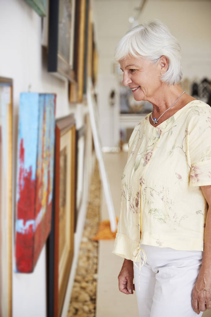 Seniorin betrachtet Gemälde in Kunstgalerie - Foto, Bild