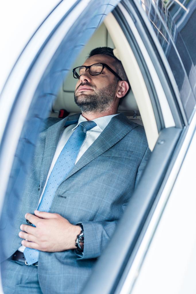 tired businessman in eyeglasses sleeping in car - Photo, Image