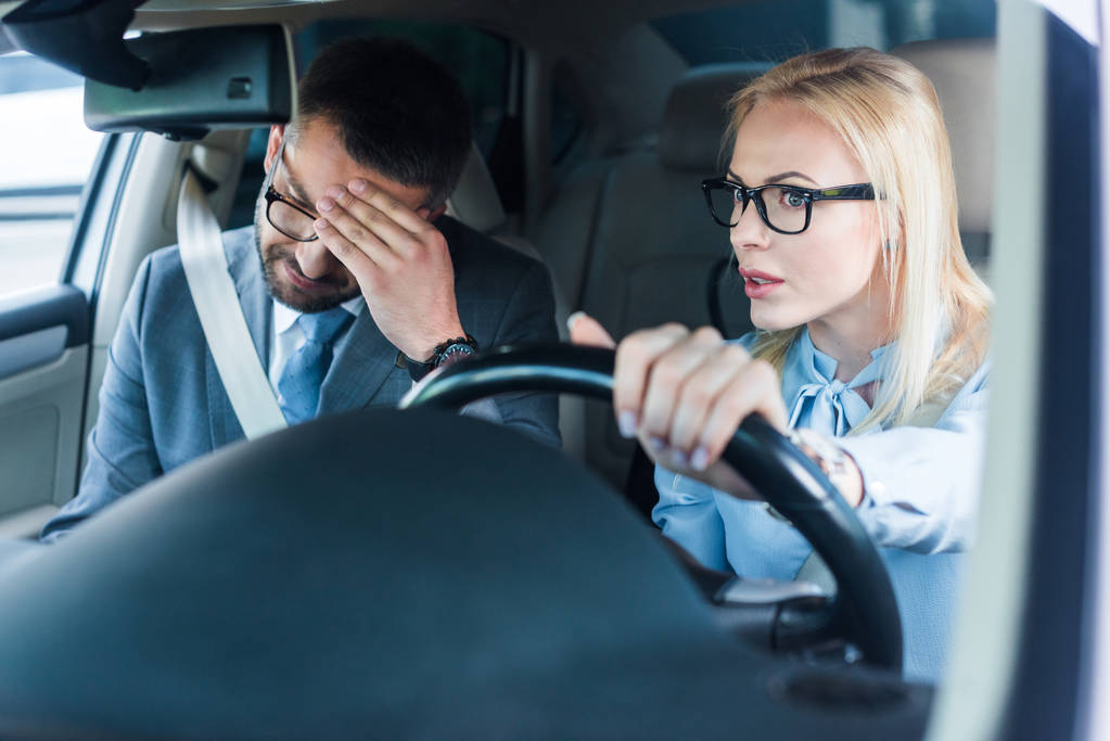 портрет блондинки-предпринимательницы в очках за рулем автомобиля с коллегой рядом
 - Фото, изображение