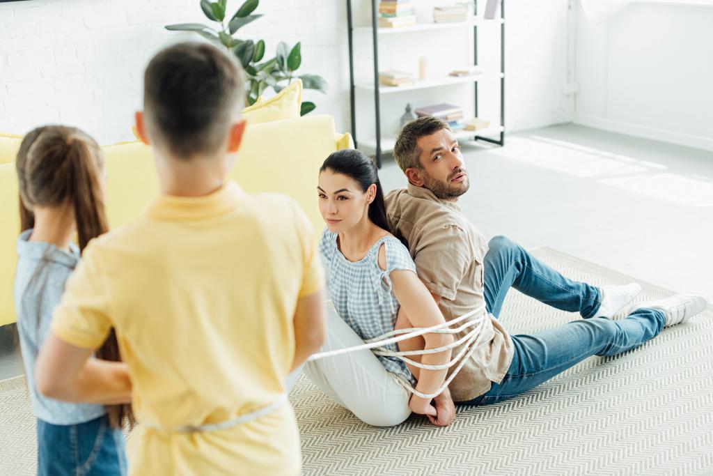 неслухняні діти зв'язують батьків з мотузкою на підлозі вдома
 - Фото, зображення