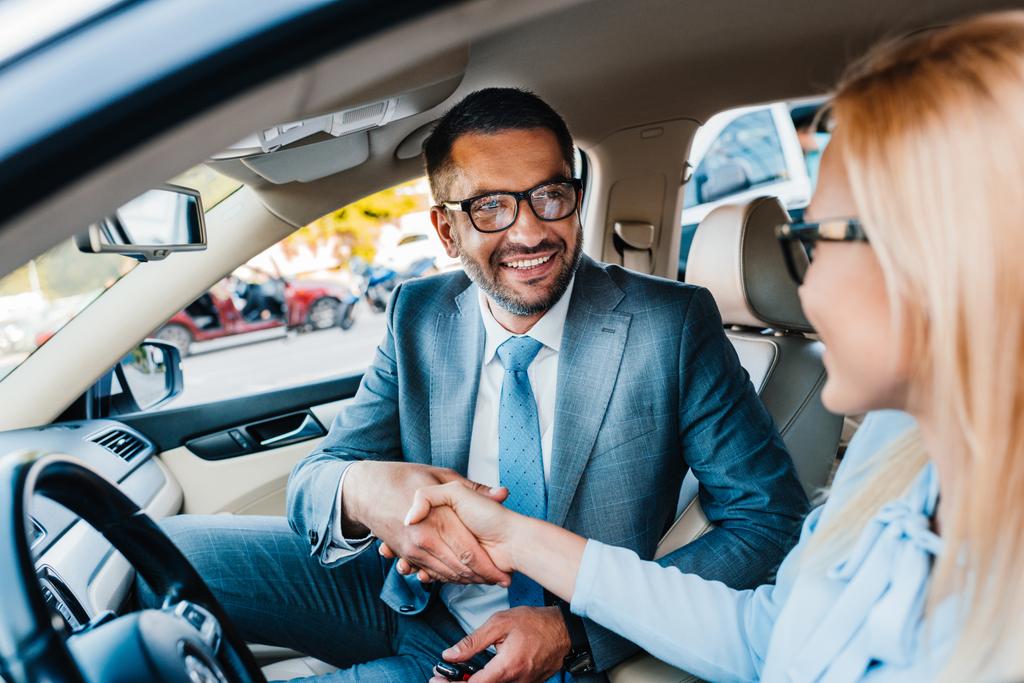 valikoiva painopiste hymyileviä liikekumppaneita kättelee autossa
 - Valokuva, kuva
