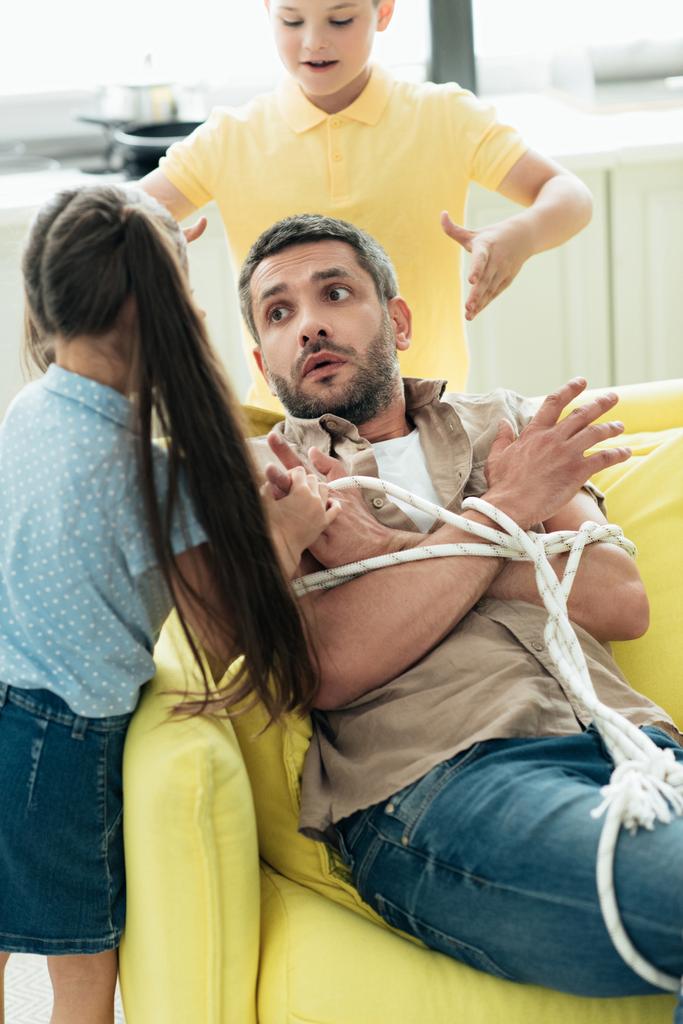 Kinder binden Vater zu Hause mit Seil, Elternschaftskonzept - Foto, Bild