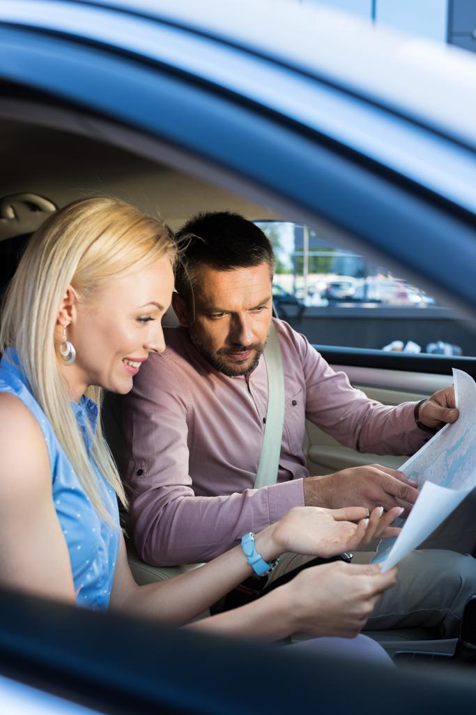 side view of couple looking for destination on map while sitting in car - Photo, Image