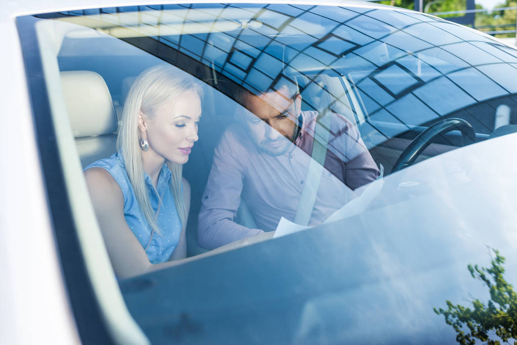 ζευγάρι ψάχνει για προορισμός στο χάρτη, ενώ κάθεται στο αυτοκίνητο - Φωτογραφία, εικόνα