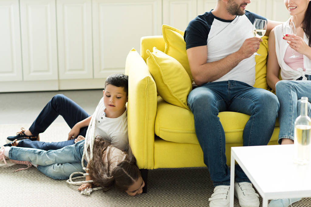батьки п'ють вино і пов'язані діти лежать на підлозі вдома, концепція батьківства
 - Фото, зображення