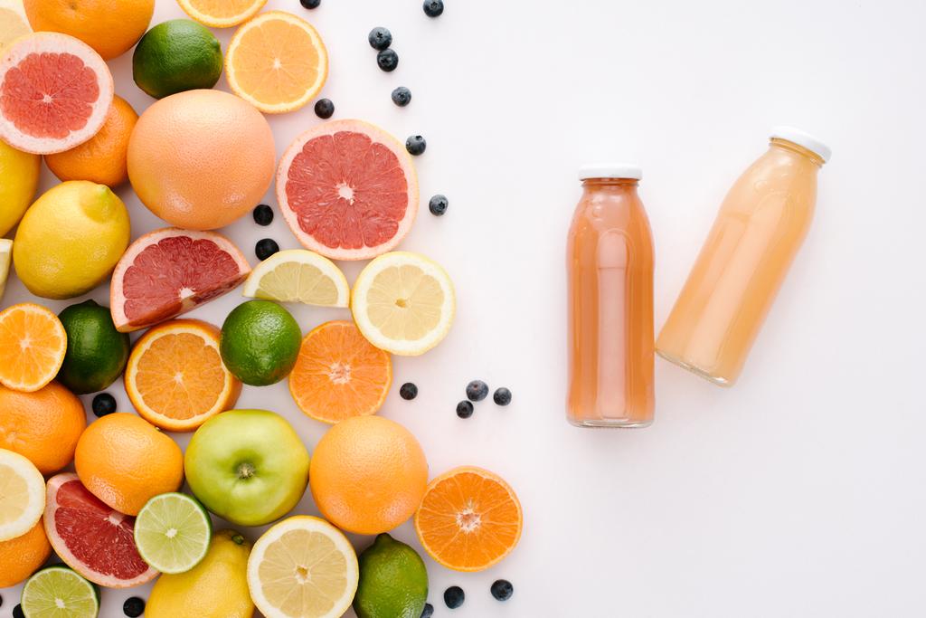 bovenaanzicht van verschillende citrusvruchten met flessen SAP op witte ondergrond - Foto, afbeelding