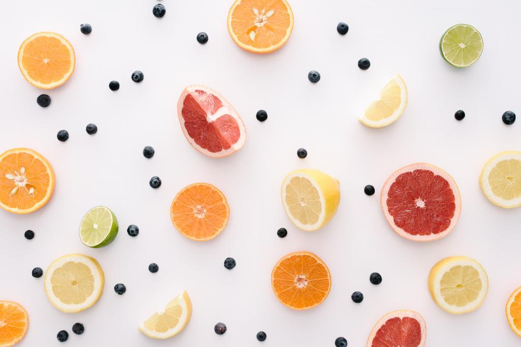 pohled shora plátky citrusových plodů a borůvky na bílý povrch - Fotografie, Obrázek