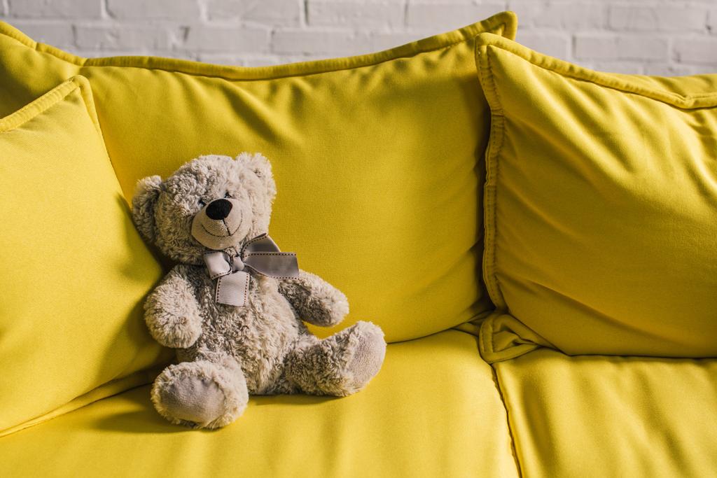 плюшевий ведмідь на жовтому дивані в затишній кімнаті
 - Фото, зображення