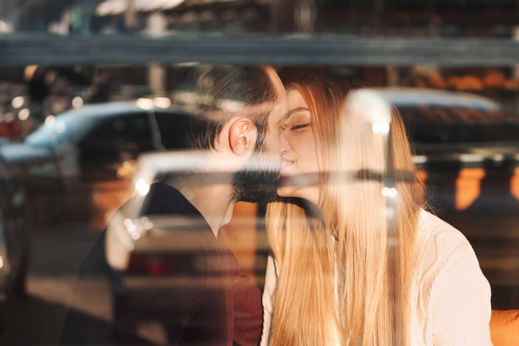 Nuori romanttinen pari suudella kahvilassa, näkymä ulkona ikkunan läpi
 - Valokuva, kuva