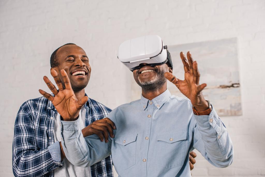 lachende jongeman gelukkig senior vader met behulp van virtual reality headset te kijken  - Foto, afbeelding