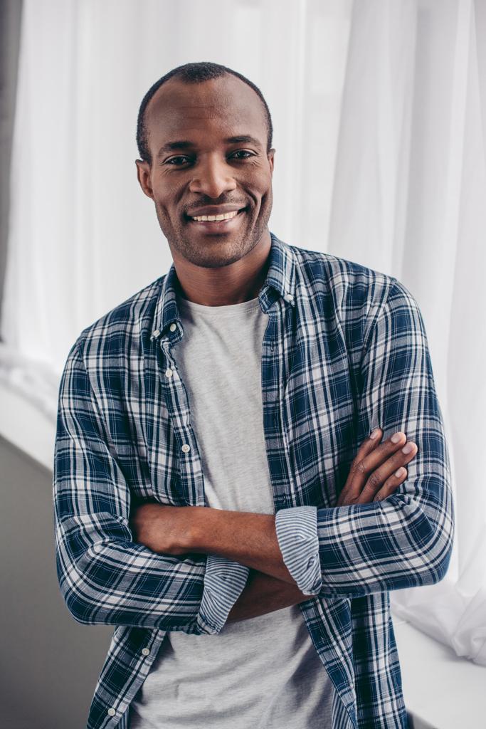 komea nuori afrikkalainen amerikkalainen mies seisoo ristissä kädet ja hymyilee kameralle
 - Valokuva, kuva