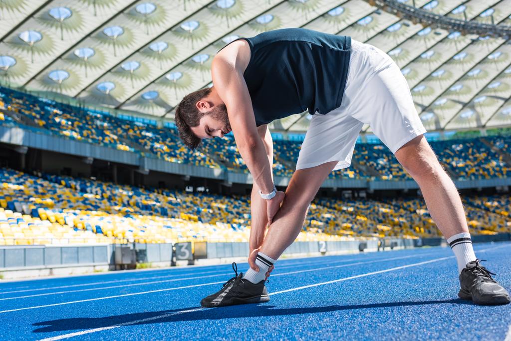 красивий молодий чоловік тягнеться на біговій доріжці на спортивному стадіоні
 - Фото, зображення