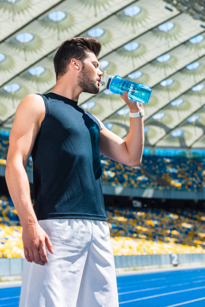 przystojny młody mężczyzna wody pitnej po treningu na stadion sportowy - Zdjęcie, obraz