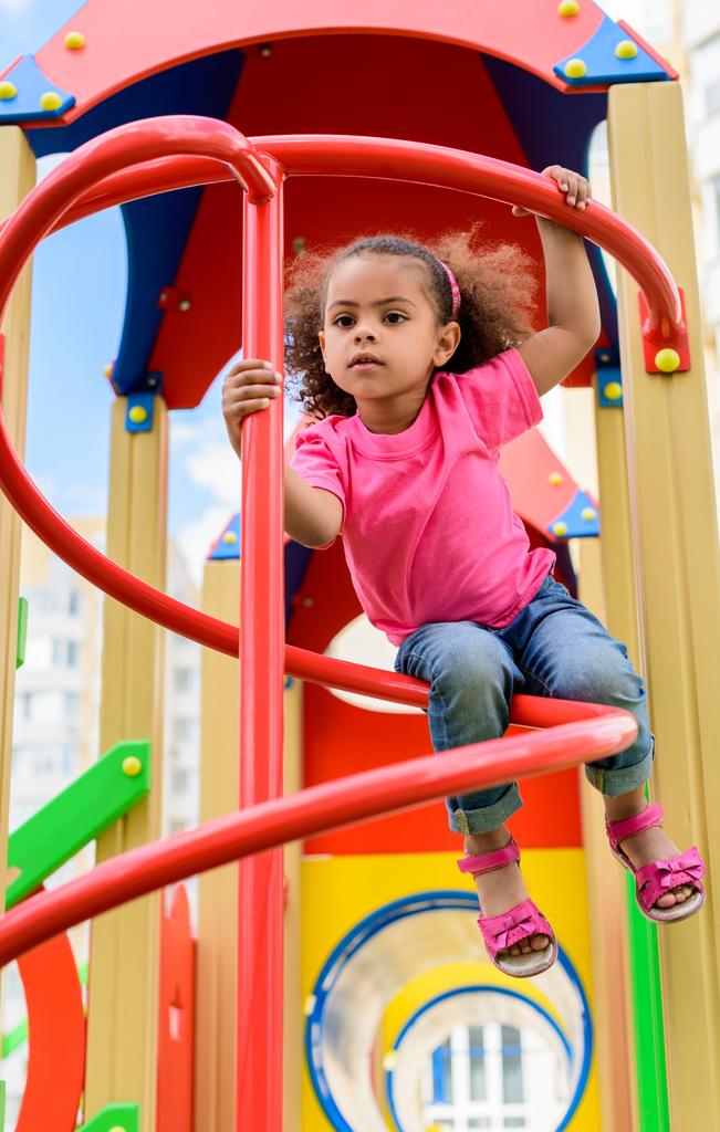 Low-Winkelansicht von lockigen afrikanisch-amerikanischen kleinen Kind Spaß auf dem Spielplatz  - Foto, Bild