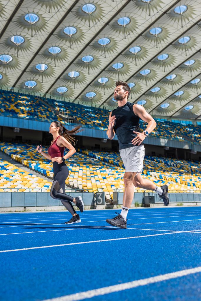 lekkoatletycznego młody płci męskiej i żeńskiej biegaczy działa na torze na stadion sportowy - Zdjęcie, obraz