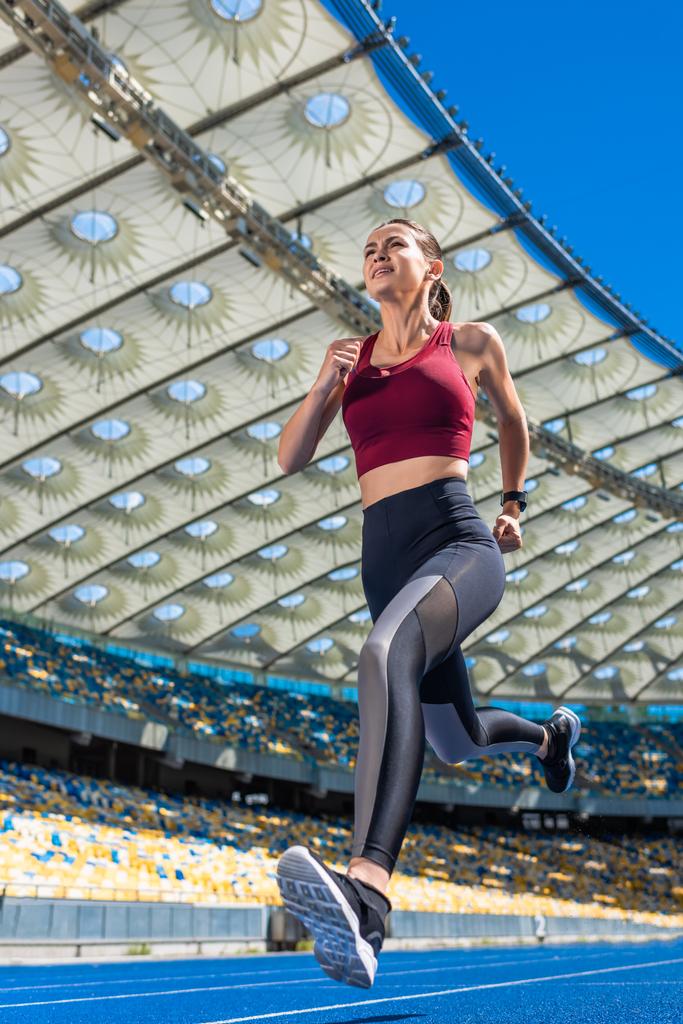 vue du bas de la jeune femme attrayante qui court sur la piste au stade de sport
 - Photo, image