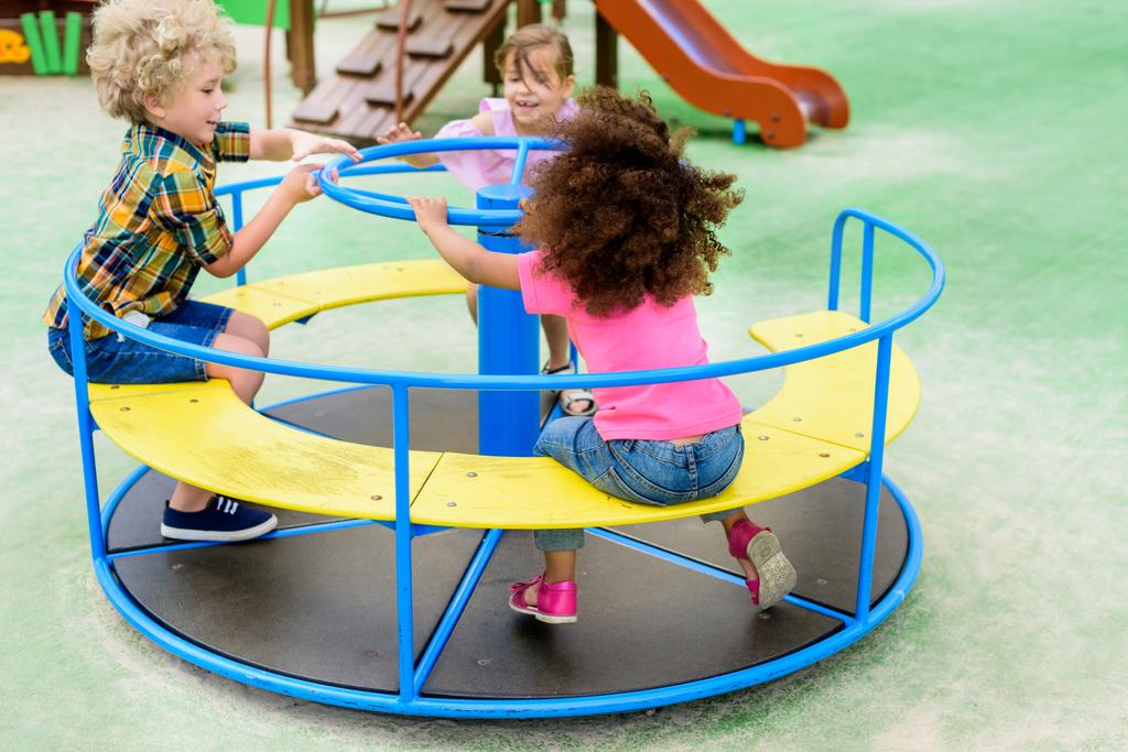 heureux adorables petits enfants chevauchant sur le carrousel à aire de jeux
  - Photo, image