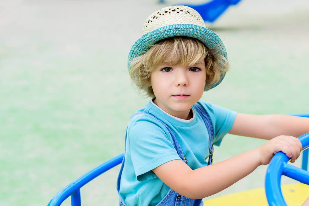 foco seletivo de adorável menino no panamá montando no carrossel no playground
  - Foto, Imagem