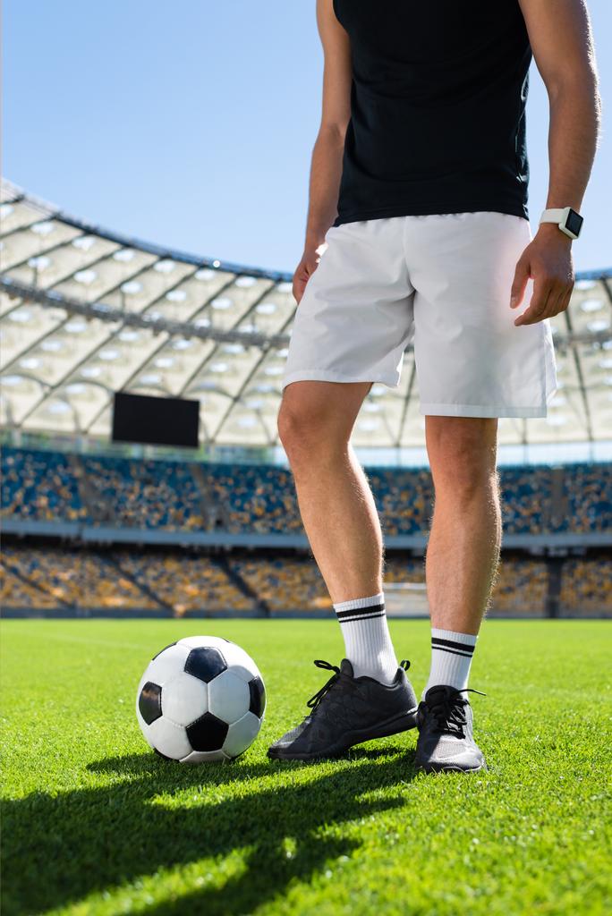 近代的なスポーツ スタジアムでボールを持って立っているサッカー選手のショットをトリミング - 写真・画像