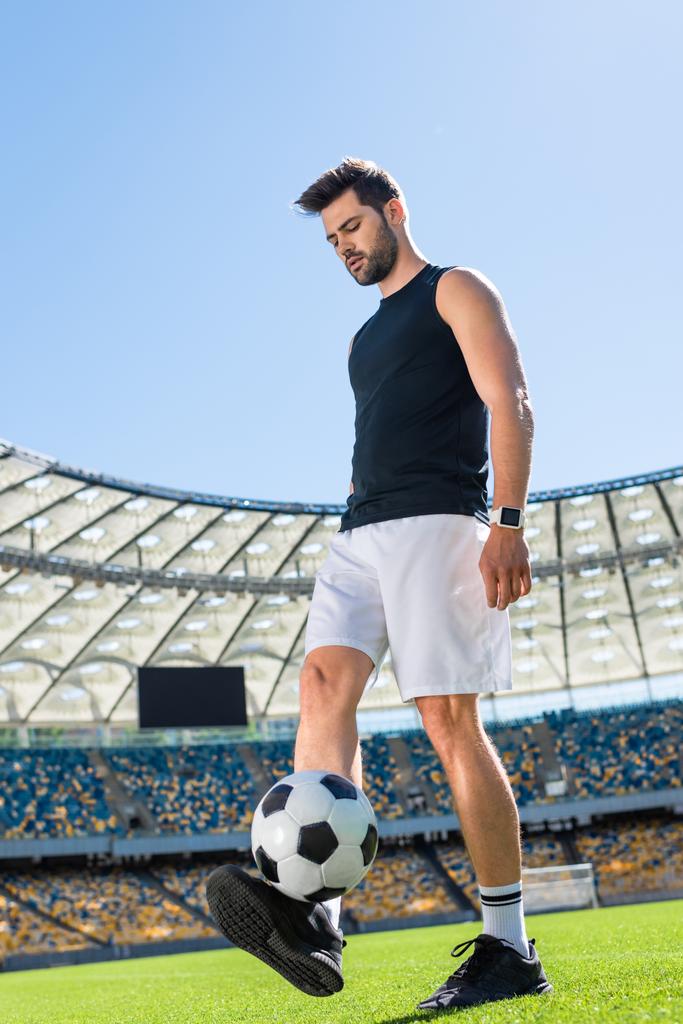 apuesto joven futbolista haciendo ejercicio con pelota en el estadio deportivo
 - Foto, Imagen