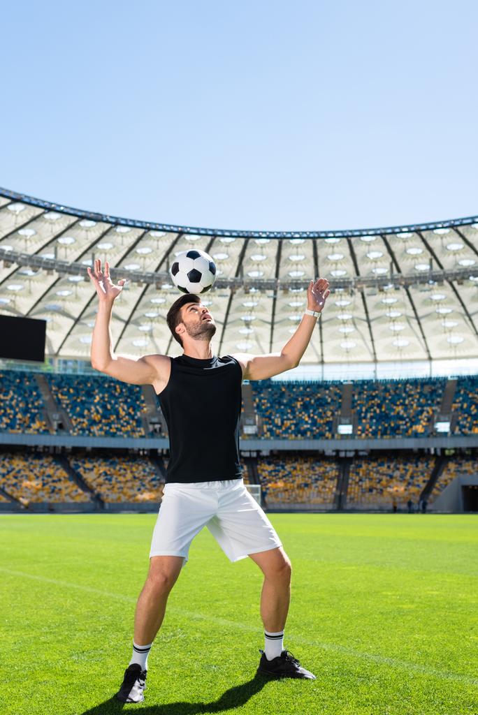 przystojny młody piłkarz równoważenia piłkę na głowę o stadion sportowy - Zdjęcie, obraz