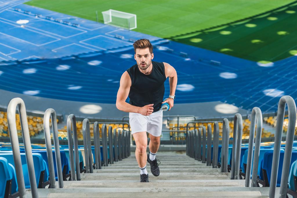 korkea kulma näkymä houkutteleva nuori mies lenkkeily yläkerrassa urheilustadionilla
 - Valokuva, kuva
