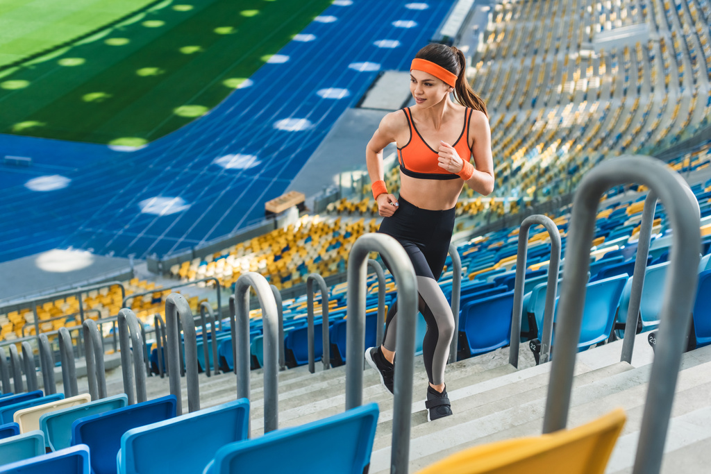 vista ad alto angolo di bella donna atletica che corre al piano di sopra allo stadio sportivo
 - Foto, immagini