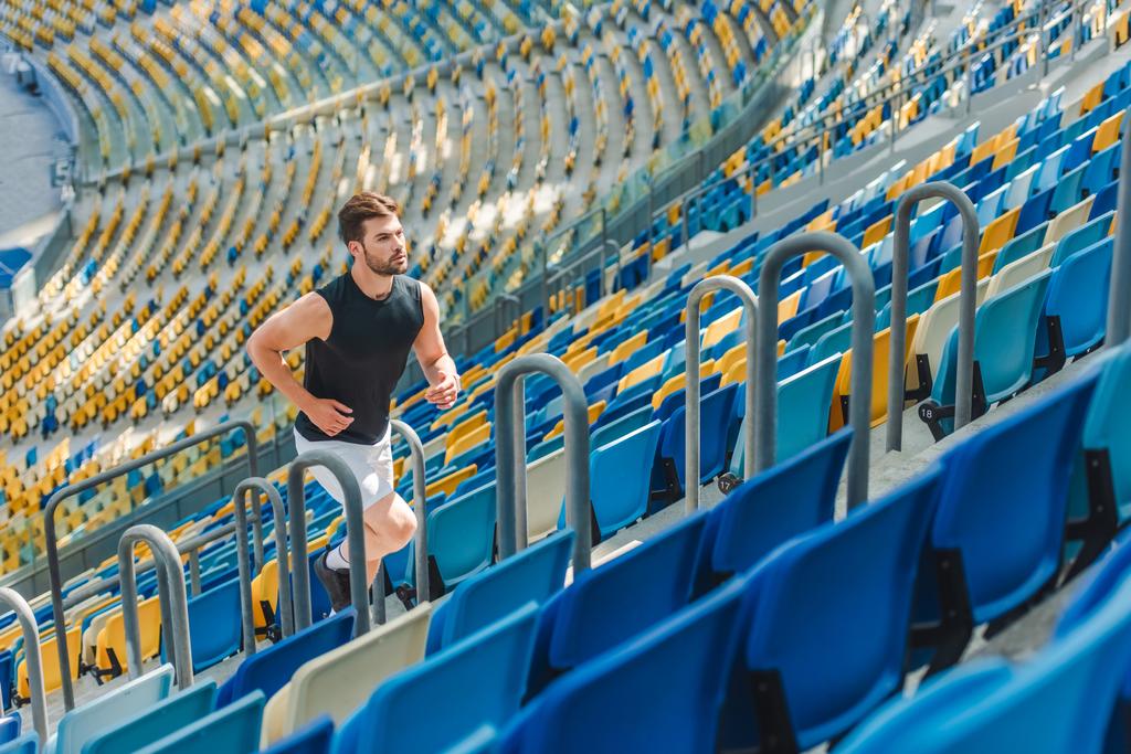 fit young man jogging upstairs at sports stadium - Photo, Image