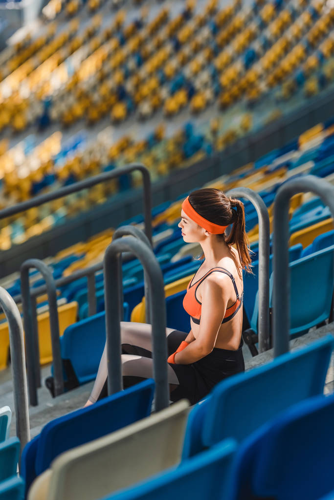 vista de ángulo alto de la hermosa mujer joven relajándose en las escaleras en el estadio de deportes
 - Foto, Imagen