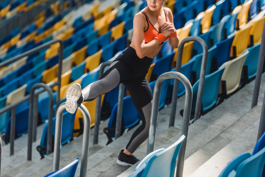 высокий угол обзора пригодности молодой женщины, растянувшейся на трибунах на спортивном стадионе
 - Фото, изображение