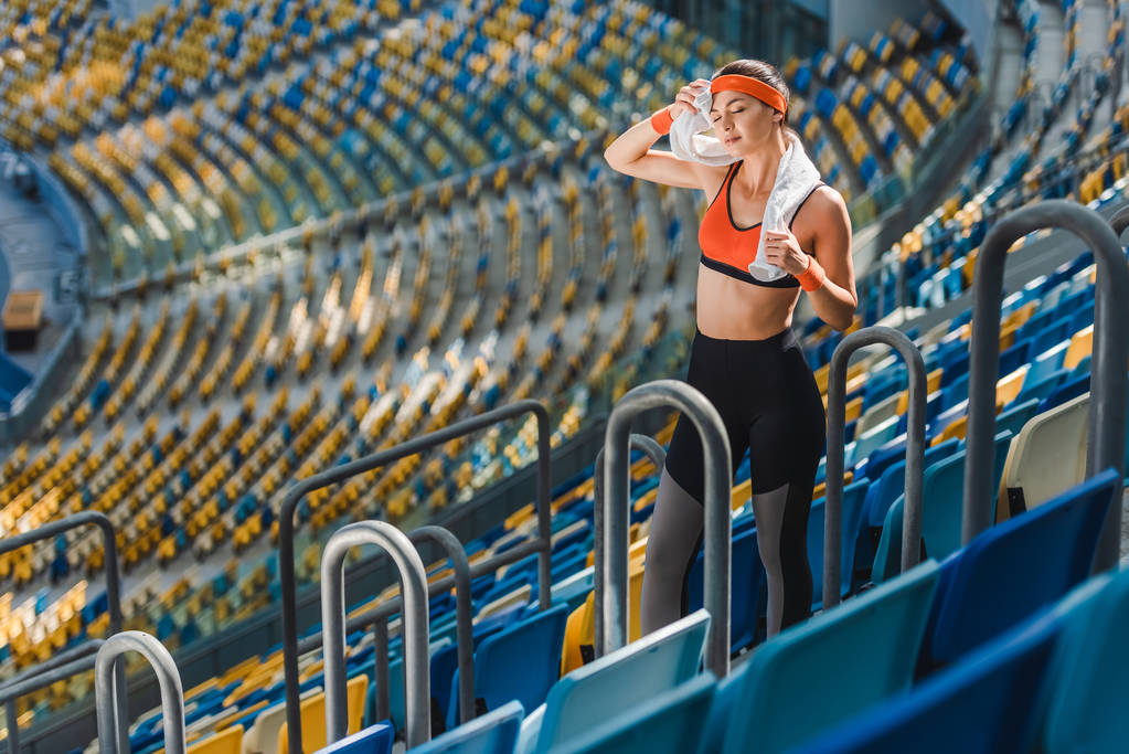 vue grand angle de la jeune femme fatiguée avec serviette au stade de sport
 - Photo, image