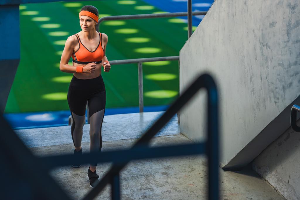 высокий угол зрения красивой молодой женщины бег трусцой на спортивном стадионе
 - Фото, изображение