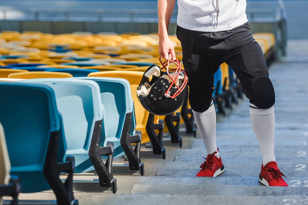 colpo ritagliato di giocatore di football americano con casco in piedi sulle scale allo stadio sportivo
 - Foto, immagini