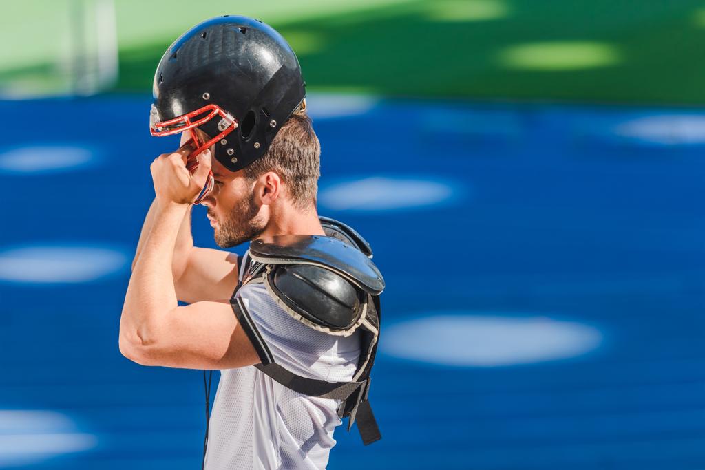 joven jugador de fútbol americano que se pone el casco en el estadio deportivo
 - Foto, imagen