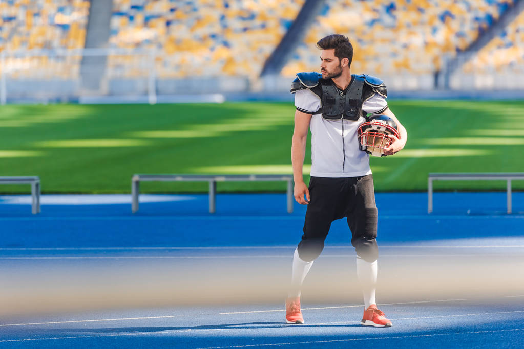 athletic american football player standing alone at sports stadium - Photo, Image