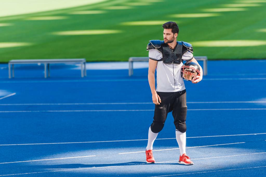 attraktiver junger amerikanischer Fußballspieler, der allein im Sportstadion steht - Foto, Bild