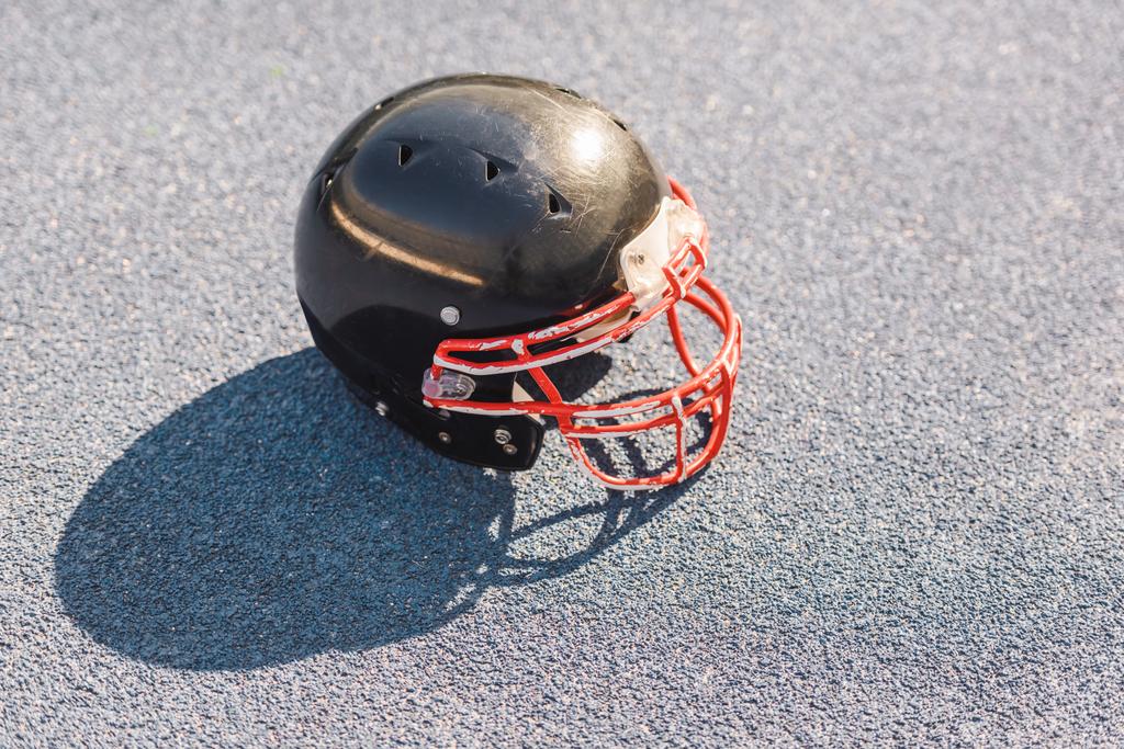 pohled z vysokého úhlu černého amerického fotbalu helmy ležící na asfaltu - Fotografie, Obrázek