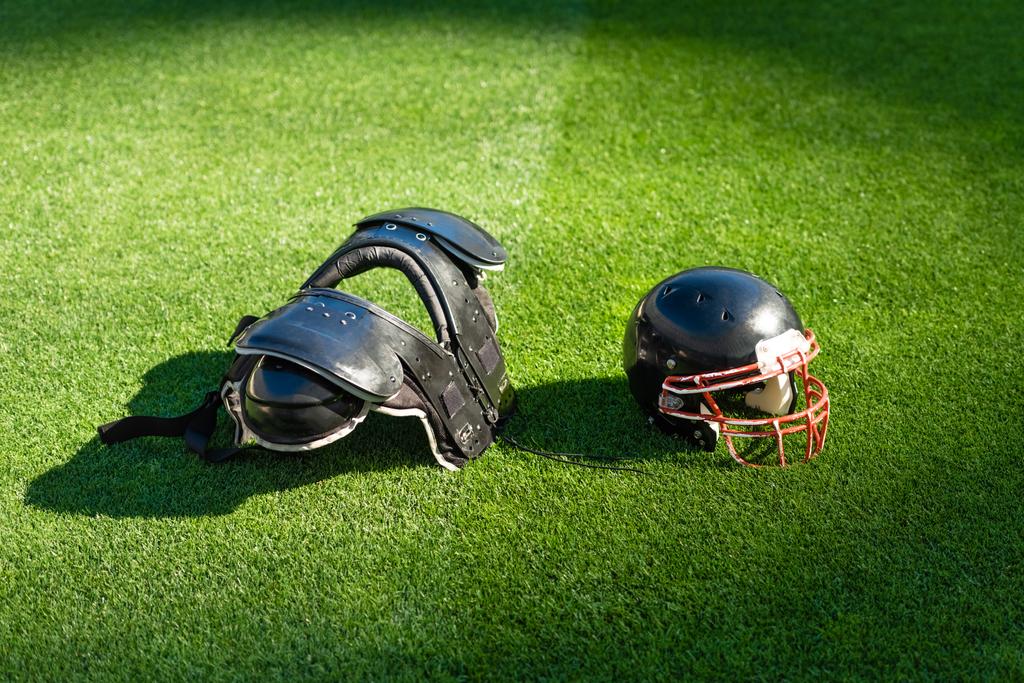 casco de fútbol americano con protección en el pecho acostado en la hierba
 - Foto, Imagen